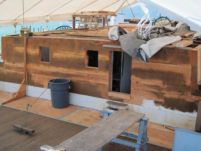 The aft house cabin under construction, with exposed plywood, tarps, and tools