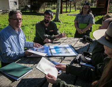 A group of National Park Staff looks over documents with a design specialist
