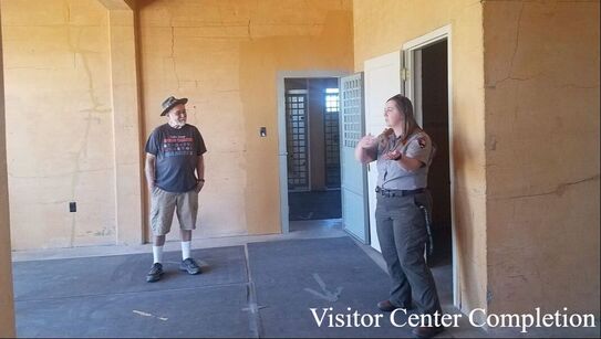 A visitor listens to a ranger inside of the historic Tule Lake jail, which has many cracked walls