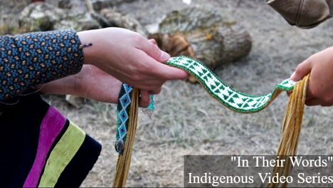 Two hands hold opposite sides of a length of beadwork with the words 