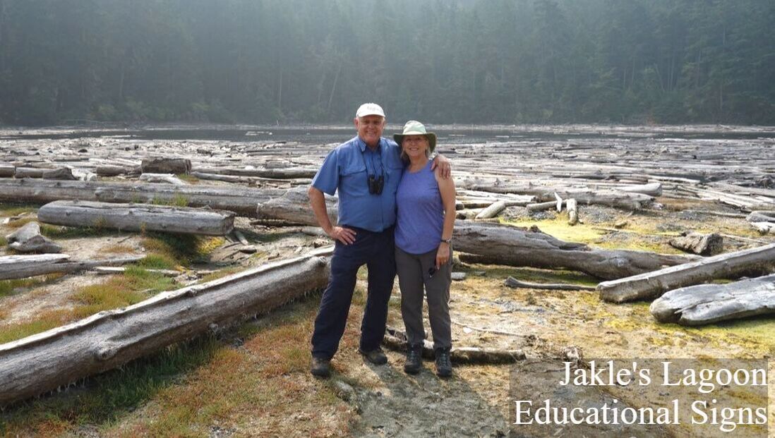 Two people stand in front of Jakle's Lagoon amidst a group of logs; the words 