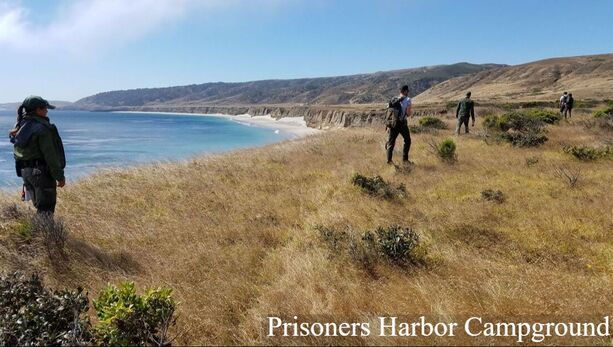 National Park Service rangers in uniform hike along a bluff on the Channel Islands