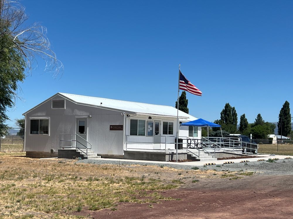 A white visitor center building with an American flag out front