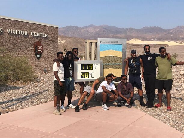 A visitor stands in front of the large thermometer at Furnace Creek Visitor Center