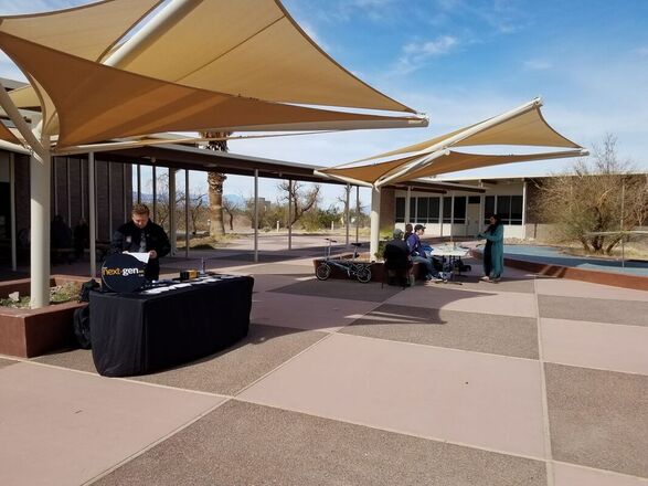 People stand at tables underneath the shade of the Furnace Creek courtyard