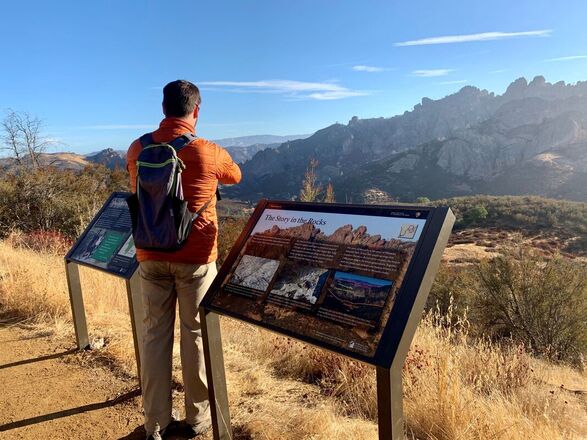 A visitor enjoys views of the Pinnacles next to two wayside educational signs