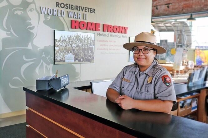 A National Park Service ranger stands at the front counter of the Rosie the Riveter WWII Home Front Visitor Education Center