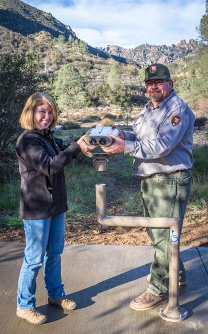 Visitor and ranger stand by mounted viewing scope