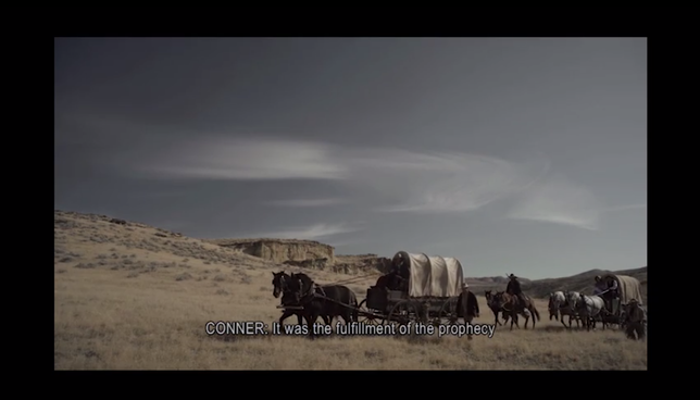 Screenshot from Whitman Mission orientation film of a covered wagon train with many horses crossing a grassy plain