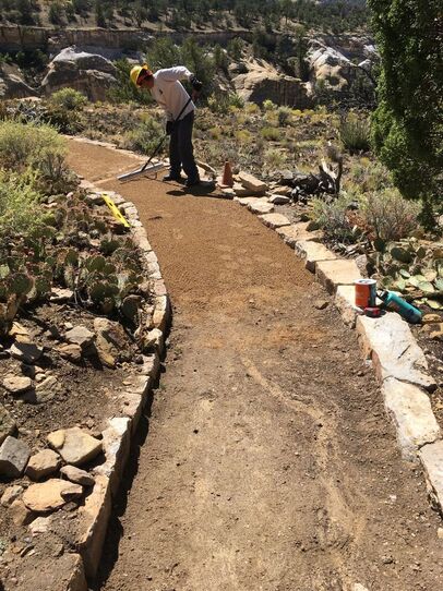 An Ancestral Lands Conservation Corps member rakes the new dirt trail surface