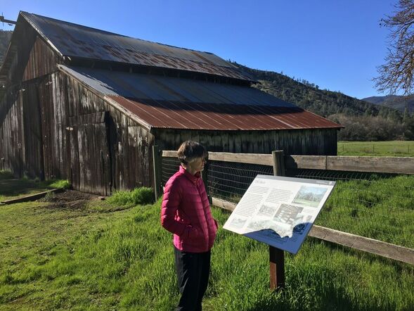Visitor reads a wayside educational sign at the historic Bacon Homestead barn