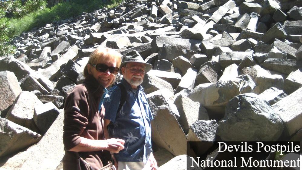 Two visitors stand in front of a pile of columnar basalt blocks