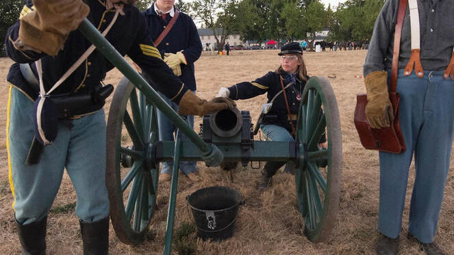 Uniformed volunteers load a cannon during a military reenactment