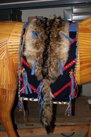 A wolf hide saddle blanket draped over the backside of a wooden horse mannequin