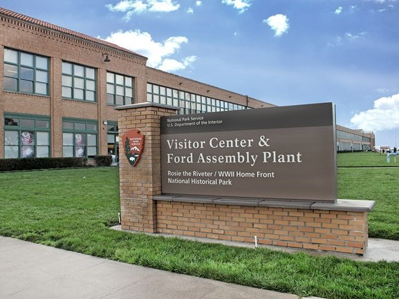 A National Park Service marquee sign titled, "Visitor Center & Ford Assembly Plant"