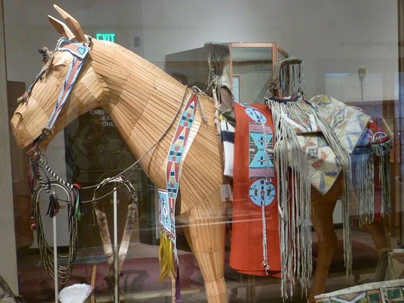 A wooden horse mannequin is adorned with various pieces of regalia with intricate beading