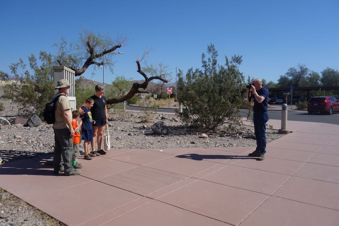 A visitor takes a picture of a family standing in front of the thermometer