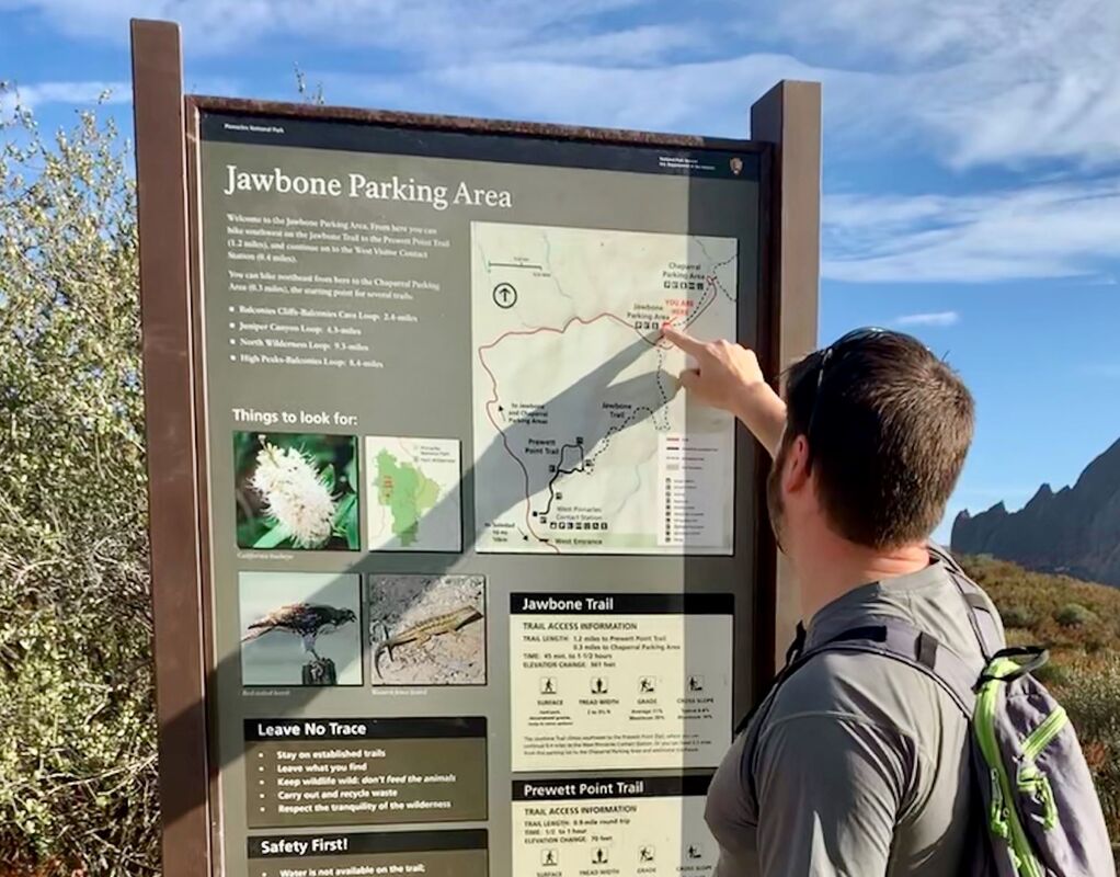 A visitor points to a map on a trailhead sign at Pinnacles National Park