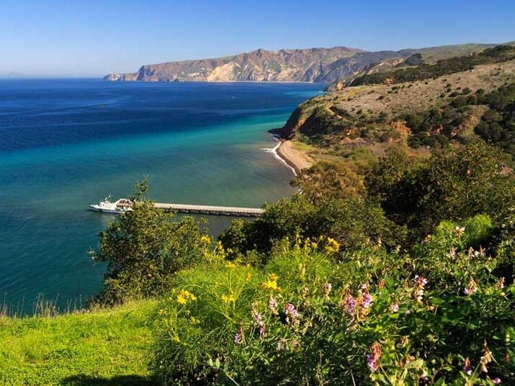 The coastline of Santa Cruz Island with a boat in dock at Prisoners Harbor