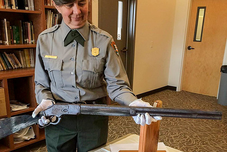 A National Park Service ranger carefully holds the forgotten Winchester