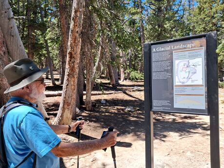 A visitor stands in front of Stella Lake looking at the Wheeler Peak ridgeline, which is dappled in snow