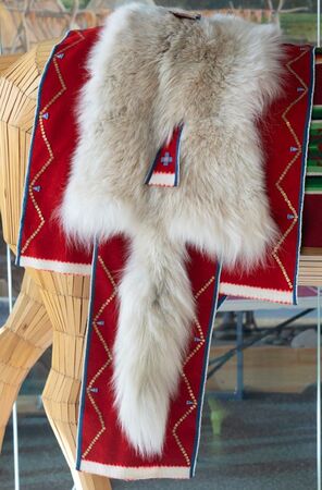 A wolf hide saddle blanket draped over the backside of a wooden horse mannequin