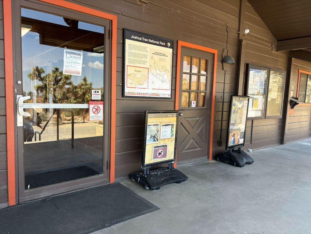 A group of signs in front of a building, including two plastic-base sign holders on the ground