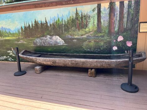 Historic Tolowa canoe sitting in front of mural