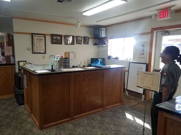 A ranger stands looking at a small counter in a lobby