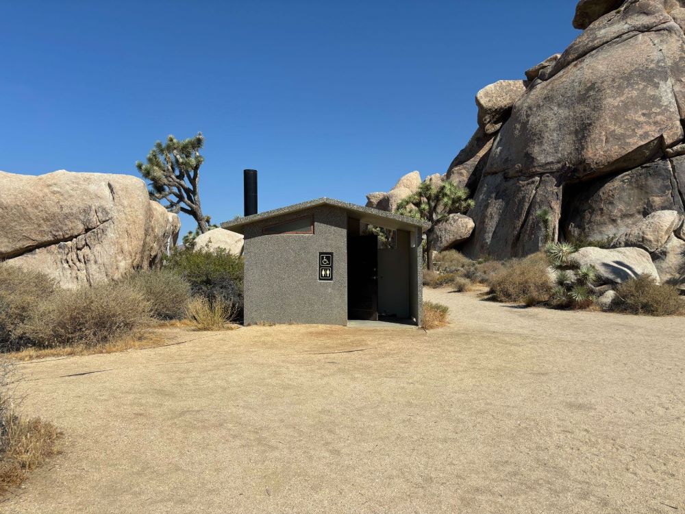 Vault toilet among large granite rocks and Joshua trees