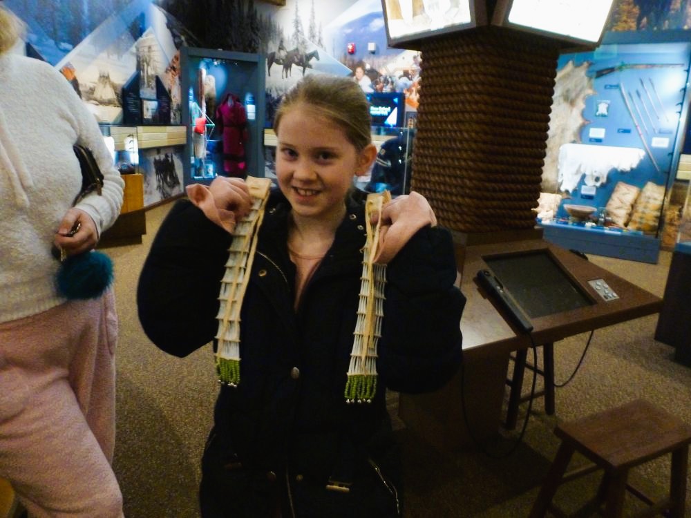 A young visitor holds beaded hair ties up next to the face to show how they might look