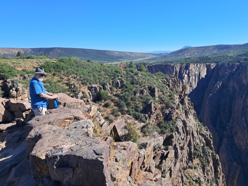 A person stands looking over the rim into the Black Canyon of the Gunnison