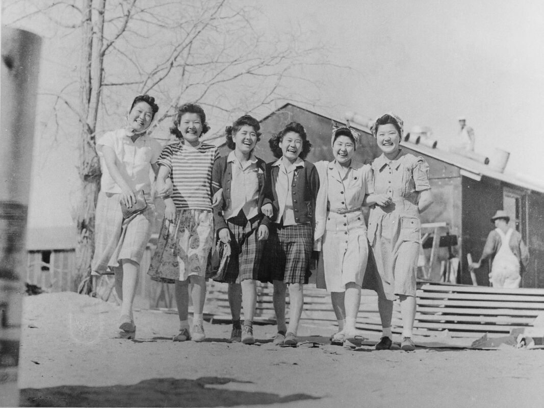 Historic photo of 6 smiling incarcerees in front of barracks at Manzanar